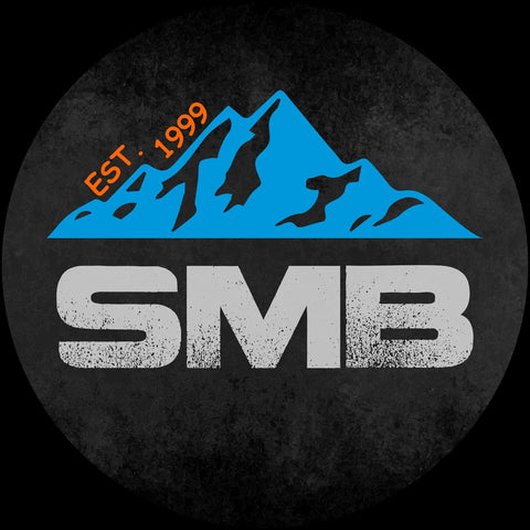 SMB logo with blue mountain design and 'EST. 1999' inscription on a circular black background