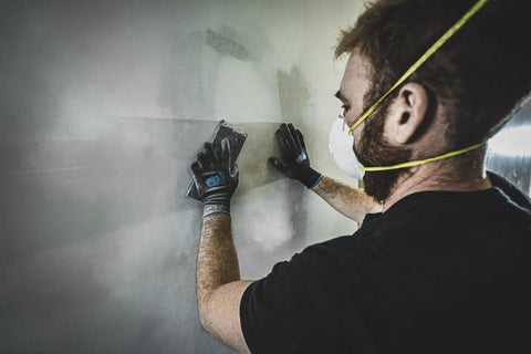 Man sanding a wall while wearing Never Slip Maximum Grip All Purpose Work Gloves For Men With Polymer Palm For Wet Dry And Oily Conditions