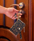 Streamlined Rfid Blocking Keychain Wallet With Genuine Leather Wrist Strap held by a hand with keys near a door lock.