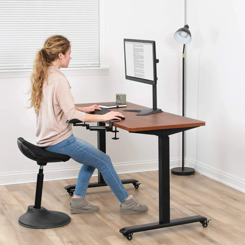 Woman using two pack clamp adjustable armrests at a desk with a computer for ergonomic support in a home office.