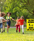 Children playing in a park with a 3 Pack Slow Down Kids At Play Signs 14.2 By 11 Inches Double Sided Weatherproof Yard Street Safety Sign