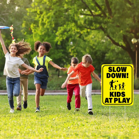Children playing in a park with a 3 Pack Slow Down Kids At Play Signs 14.2 By 11 Inches Double Sided Weatherproof Yard Street Safety Sign