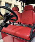 Heavy Duty Six Passenger Electric Golf Cart With Six Point Three Kilowatt AC Motor And Forty Eight Volt Electronics Built In Solar Panels Remote Key Fob And Dope Candy Apple Red Paint For No Sweat Fairway Cruising interior showing red seating and steering wheel.
