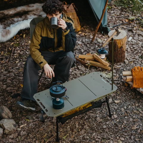 Person at campsite using Grab And Go Tactical Camping Table With Adjustable Height From 14 To 23 Inches for cooking