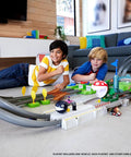 Children playing with Hot Wheels Mario Kart Circuit Track Set With 2 Die Cast Vehicles, High Speed Racing Playset Featuring Mario And Yoshi Karts, Booster Pack Included, Amazon Exclusive Gift For Kids And Collectors in a living room.