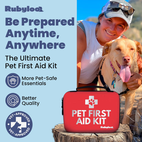 Front view of a red Pet First Aid Kit case with white cross and Rubyloo logo, beside a dog and smiling woman outdoors.
