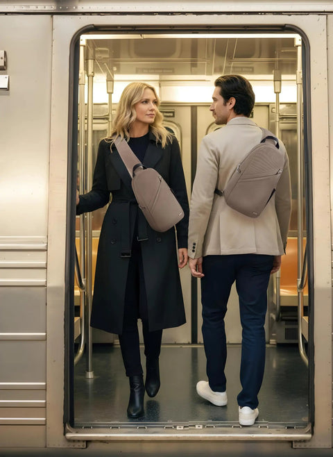 Two people wearing Anti Theft Sling Bag With Locking Zippers standing in subway doorway.