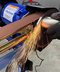 Grinding metal with a 1HP belt sander and bench grinder combo, featuring sparks, 2x48 inch sanding belt, and ergonomic grip.