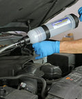 Side view of Mityvac 1.5 L fluid evacuator in use under car hood with blue-gloved hands and attached hose.