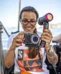 Person holding camera with Underwater Photo And Video Light Beast 2500 Lumen COB LED, demonstrating wide beam capability outdoors