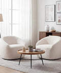 Living room setup with two White Boucle Swivel Chair With 360 Degree Base, Oversized Round Barrel Accent Chair For Living Room, Super Cozy And Extra Comfy Ergonomic Design, Wide Seat For Back Support And Lounge Vibes around a wooden coffee table, soft natural light from large window in background