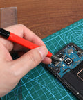 Hand using Drilling Cleaning Pen With Fiberglass Brush And Precision Abrasive Stick for electronic device repair.