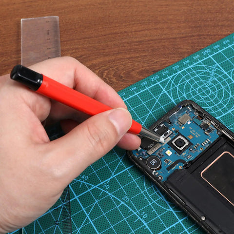 Hand using Drilling Cleaning Pen With Fiberglass Brush And Precision Abrasive Stick for electronic device repair.
