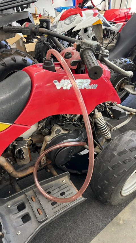 One Half Inch X Eight Foot Self Priming Jiggler Siphon Hose Transfers Gas Water Oil Fast Up To Four Gallons Per Minute on a red ATV engine.