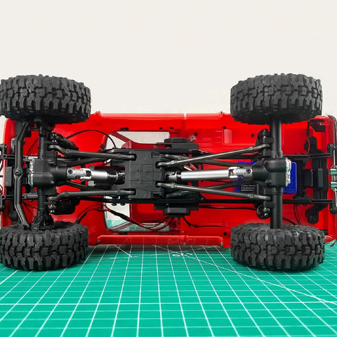 2 Pack Steel CVD Driveshafts For 1 To 18 TRX4 M K10 F150 RC Crawler Upgrades Silver Beefy Heavy Duty Connection For Smooth Power Transfer And Precision Fit Ideal RC Crawler Upgrade For Stability And Durability, underside view of red 1/18 RC crawler chassis with steel driveshafts