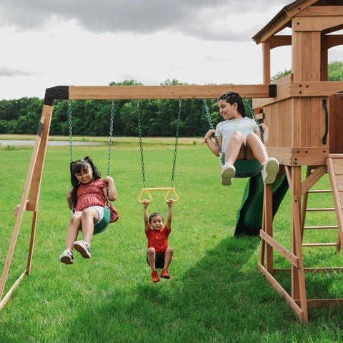 Children playing on a Cedar Wood Swing Set With Wave Slide And Raised Clubhouse Plus Balcony, Wooden Bridge, Rock Wall