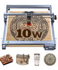 Front view of Creality 10W laser engraver on wood bed; shows four items: wallet, bag, tumbler, mandala coaster.