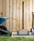 Rolling Lawn Aerator 18 Inch Rotary Push Tine Spike Soil Aerator with 3 Piece Long Steel Handle against wooden fence