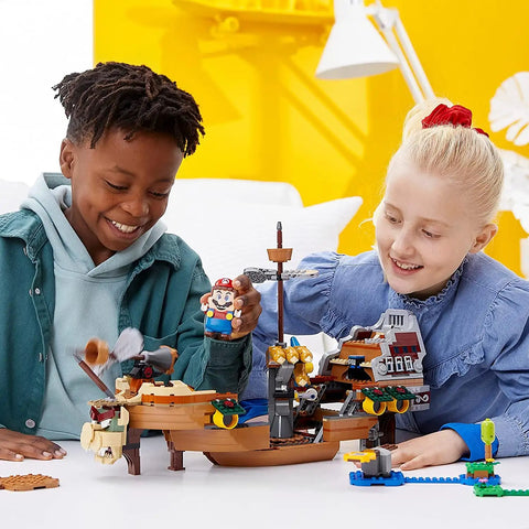 Children playing with Super Mario Bowser’s Airship Expansion Set 71391 on a table, featuring buildable airship and Mario figure.