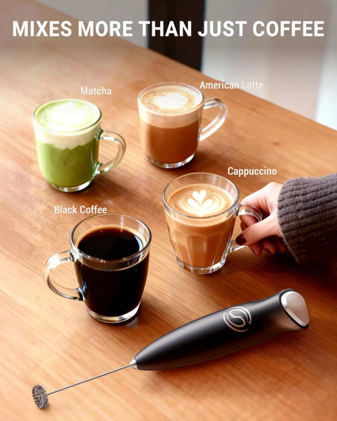 Handheld Milk Frother Wand With 2 Whisks, Electric Coffee Mixer For Creamy Foam, One-Press Operation next to various drinks on table.