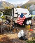 Heavy Duty RV Flag Pole Mount For Travel Trailer Tongue Jack Clamps On Without Drilling Dual Pole Holder For Two To Two And A Quarter Inch Tongue Brackets And One Inch Flag Poles Easy Install Secure Fit For Campers beside RV at campsite with mountains in background