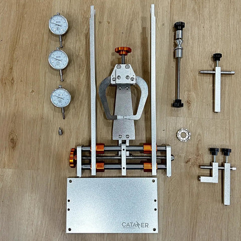 Beefy Wheel Truing Stand For Bicycle Adjustment And Rim Truing With Pro Grade And Adjustable Rim Width 50 To 200mm For MTB Road BMX And City Bikes Made From 7075 Aluminum Alloy Includes Roller Head And Three Test Tables For Brake Disc Alignment, laid out with tools on wooden surface