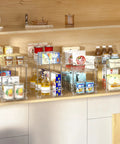 Slick Clear Under Sink Organizers And Storage Bins 2 Pack With High Low Design For Bathroom Cabinet Decluttering Pantry Organization, featuring stacked bins with various goods.