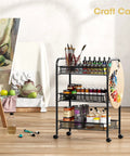 Three Tier Metal Rolling Cart With Mesh Wire Shelving And Wheels filled with art supplies in an art studio, showing side hooks.