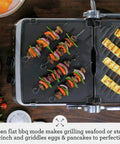 Breville Stainless Steel Electric Grill Panini Maker With One Touch Presets grilling vegetable skewers and grilled pineapple slices.