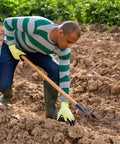 Man using Beast Of A Handheld Manure Fork For Farm And Garden Use With Five Solid Tines on a field