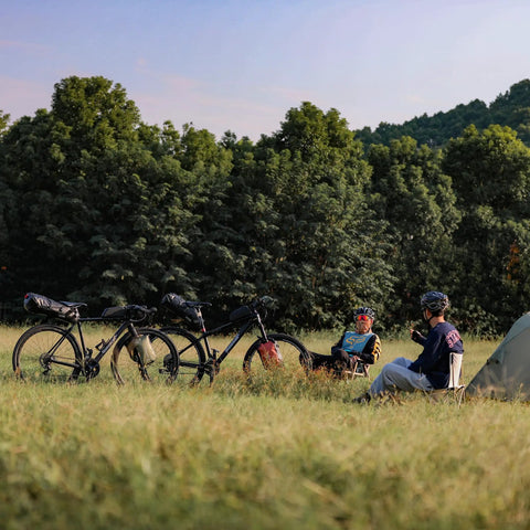 Cyclists resting in a field with bikes using Waterproof Bike Saddle Bag 10L For Road And Mountain Biking PVC Seamless Welded Seat