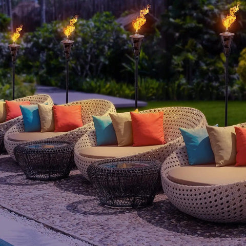 Outdoor Metal Patio Torches Set Ideal For Deck Patio Backyard Outdoor Parties And Weddings Includes Fiberglass Wick And Snuffer Cap 4 Pack Long Lasting Five Hour Flame With Citronella Oil Not Included illuminating a patio area with chairs and cushions.