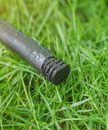 Wet black end cap from DIY Ready 1/2 Inch Drip Irrigation End Cap Kit With 15 Barbed End Plugs on green grass