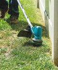 Cordless 13 Inch String Trimmer With Brushless Motor 18V LXT Power 4.0Ah Battery Kit detailing lawn edging along a fence.