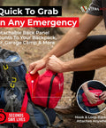 Red compact first aid kit with zipper, attached to blue hiking backpack via hook-and-loop; VitalHouse logo visible