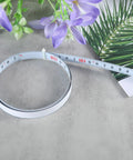 Precision Folding Tape Measure And Measuring Ruler Kit For Tough Woodworking Jobs High Visibility White Finish laid out with flowers.