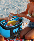 XL Beach Tote Bag With Insulated Cooler Compartment And Wet Dry Separation, filled with beach items, on sand with people