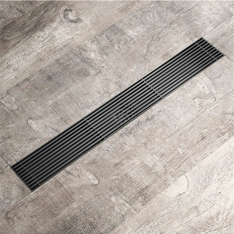 Sleek Linear Shower Drain In Heavy Duty Stainless Steel With Removable Grate And Hair Catcher For Hassle Free Bathroom Drains Finished In Slick Rose Gold on wooden floor.