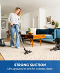 Using Quiet Bagless Canister Vacuum With Kickass Suction For Whole Home Cleaning on carpet, woman vacuuming living room.