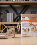 Tachometer Model Kit For Adults, Hands On Wooden STEM Puzzle, DIY Mechanical Science Project shown with packaging on a table.