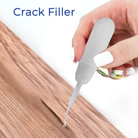 Hand applying Beast Mode Power Bond Cyanoacrylate Glue With Activator Kit to wooden crack, close-up view.