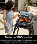 Woman using Woodfire Pro Connect Deluxe XL Backyard Grill and Smoker With Bluetooth App Control, cooking two chickens.
