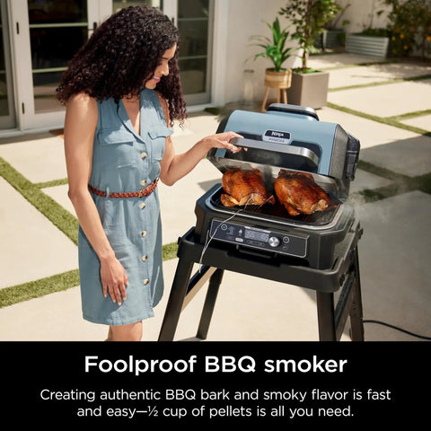 Woman using Woodfire Pro Connect Deluxe XL Backyard Grill and Smoker With Bluetooth App Control, cooking two chickens.