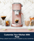Compact Espresso Machine And Cold Brew Coffee Maker With Automatic Milk Frother Wand For Next Level Hot Iced Coffee Crafts And Dope Daily Sips In Sleek Rose Pink on kitchen counter with drinks.