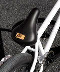 Close-up of black seat and tire on BMX Freestyle Bike With Durable Steel Frame In White, Available In 16, 18, 20, 26, And 29 Inch Sizes
