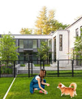 Woman playing with dog near Tall Garden Fence 36 Inch High 10 Panel Heavy Duty Metal Dog Fence for Yard Outdoor Pet Playpen, house in background.
