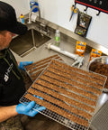 Heavy Duty Food Dehydrator With Digital Thermostat And Set It Forget It Timer Six Grease Resistant Stainless Steel Trays 650 Watt Quick Dry Motor For Even Heat Distribution Ideal For Batch Cooking Jerky Meals At Home with trays of jerky being prepared.