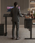 Man in suit using Rock Solid L Shaped Electric Standing Desk Triple Motor Height Adjustable Corner Workstation Sixty Three Inch.
