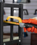 KATA mini hacksaw cutting a metal frame; yellow blade, aluminum frame, orange-gloved hand