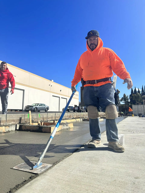 Worker using trowel on concrete wearing Leatherhead Kneepads With Ultra Soft Cushioning For Knee Fatigue Reduction, Non Slip Neoprene Straps